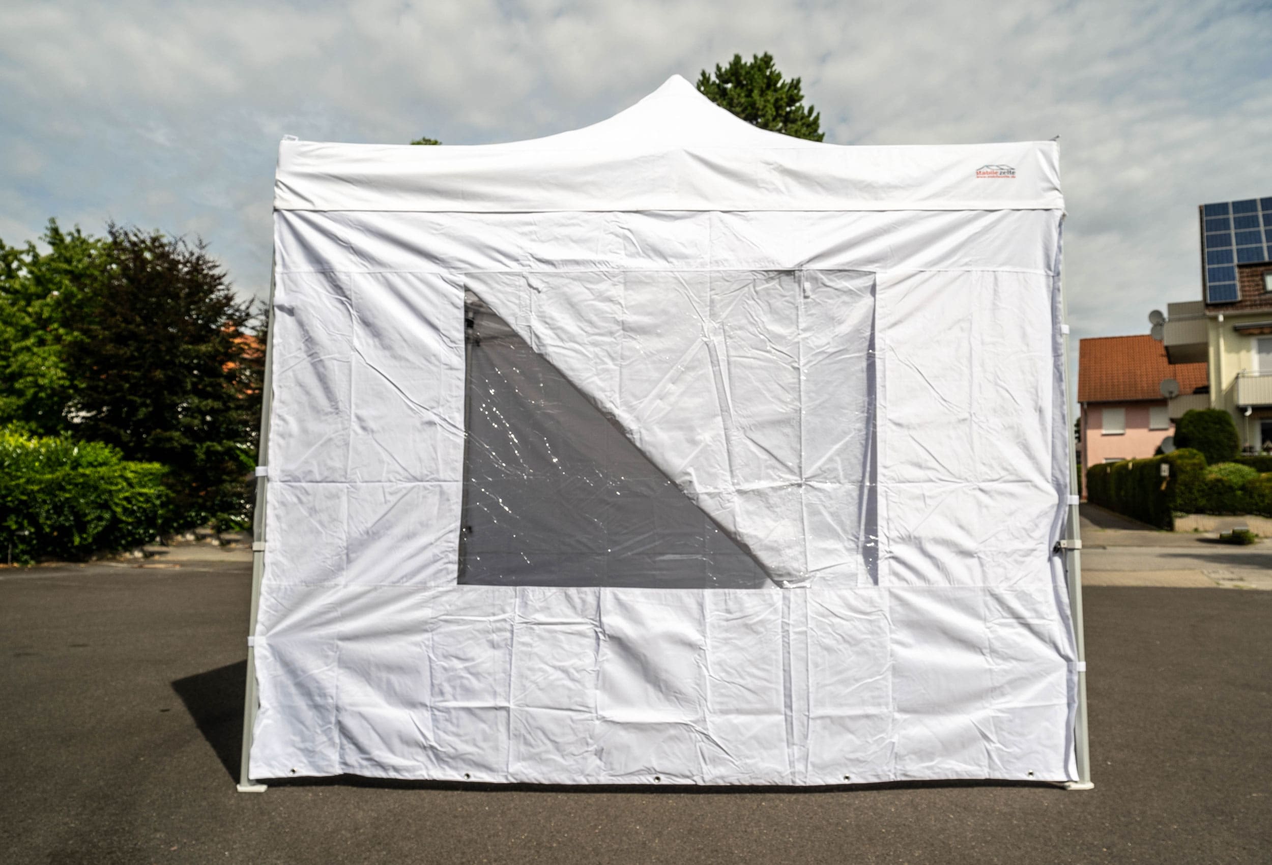 Weißes Faltzelt mit Fenster aufgebaut auf einem asphaltierten Platz