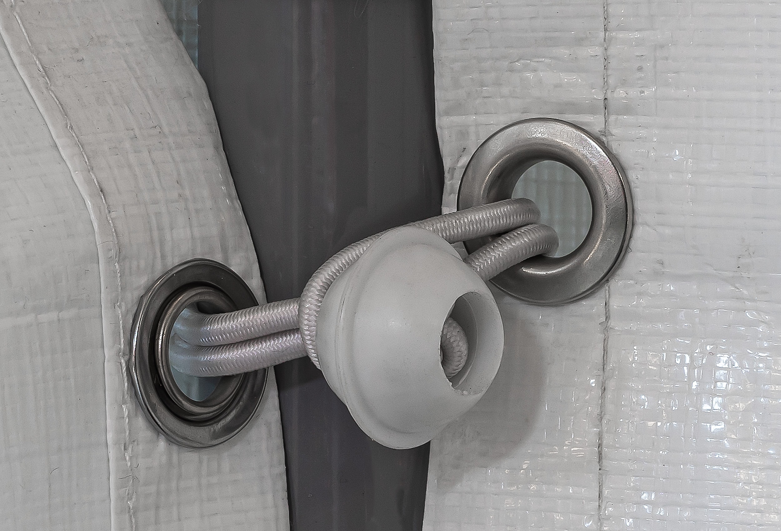 Detailansicht eines Spanngummis, welcher zwei Planen an einem Gestänge befestigt